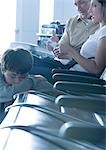 Family sitting in airport lounge, boy sleeping