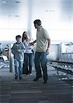 Family hurrying through airport, man reaching back to wife