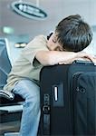 Boy resting head on suitcase, sleeping