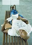 Male student lying on bench, reading