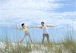 Man and woman doing side stretches on beach