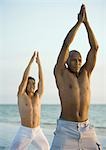 Two men doing relaxation exercise on beach