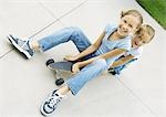 Two girls sitting on skateboard together