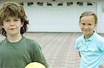 Boy and girl standing in front of driveway, smiling