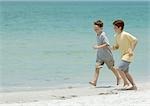 Boys running next to surf on beach