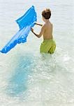 Boy carrying air mattress in sea