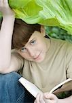 Boy reading under leaf