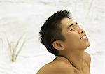 Young man on beach with head back and eyes closed