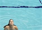 Woman standing in pool, head back and eyes closed, front view