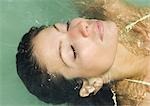 Femme avec les yeux fermés, se penchant vers l'eau, près de la tête
