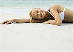 Femme allongée sur la plage, souriant à la caméra