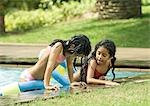 Two girls leaning on edge of pool, talking