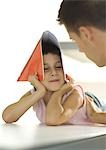 Girl holding notebook over head, turning toward father