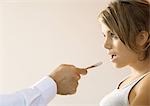 Doctor holding out tongue depressor toward young woman's mouth