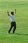 Golfer standing with arms in the air, full length