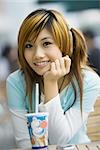 Young woman sitting with fast food drink, smiling at camera