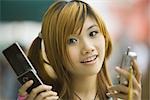 Young woman holding two cell phones, looking at camera
