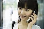 Young woman using cell phone, smiling
