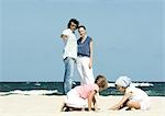 Family on beach, parents watching daughters play in sand