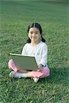 Girl sitting in grass using laptop