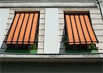 Two striped awnings pulled down over windows, low angle view
