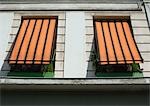 Two striped awnings pulled down over windows, low angle view