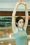 Young woman stretching arms overhead, eyes closed