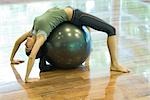 Young woman doing backbend on fitness ball