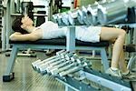 Woman lying on weight bench, doing sit-ups