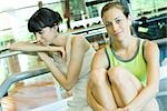 Two young women sitting in weight room