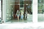 Two young women walking toward doorway together, front view