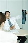 Doctor sitting across from female patient, holding up x-ray