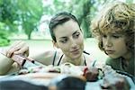 Boy looking at meats cooking on barbecue, woman glancing at him