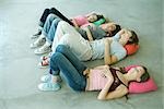 Four teen friends lying on backs on floor with knees up