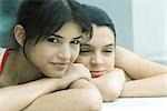 Teen girl and young woman resting heads on arms, smiling