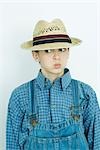 Teen girl wearing overalls and straw hat, making face