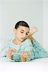 Girl lying on stomach, filing nails