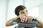Teen girl with stack of homework, listening to headphones, portrait