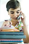Teen girl avec pile de travail à domicile, à l'aide de téléphone portable et enclos