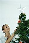 Woman placing star on top of Christmas tree