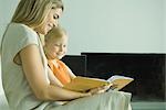 Woman reading book with little girl