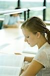 Young woman studying in university library, side view