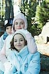 Teen girl with preteen boy and girl, wearing winter coats and hats, portrait