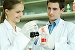 Junge männliche und weibliche Wissenschaftler halten Sie Lösungen in Labor-Glaswaren