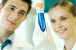 Young male and female scientists, woman holding up test tube