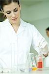 Weibliche Wissenschaftler arbeiten mit verschiedenen Lösungen im Laborglas