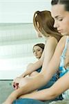 Teenager-Mädchen und junge Frau sitzen nebeneinander, die man selbst im Spiegel betrachten
