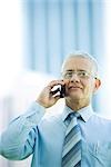 Mature businessman using cell phone, smiling, front view