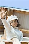 Girl waving to camera from deck of chalet, low angle view