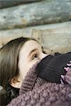 Teenage girl holding edge of sweater neck over face, looking up, close-up